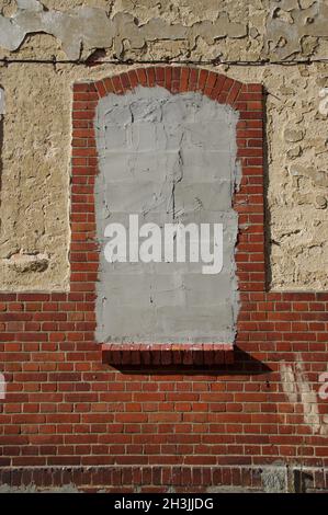 Ein gemauertes Fenster in einem alten Gebäude. Ein Loch in einem vergessenen Haus. Stockfoto