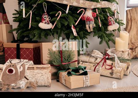 Schöne holdiay DIY handgemachte Wohndekoration. Gemütliches Zimmer mit Kerzen und Weihnachtsbaum mit Geschenken darunter dekoriert. Heißes Getränk auf dem Tisch. Ne Stockfoto