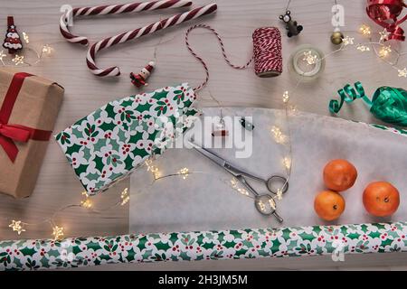 Weihnachtskomposition. Geschenkschachteln, Geschenkverpackungen mit Papier und Band, Lichter, Süßigkeiten Stöcke auf Holz Hintergrund. Holdiay DIY handgemachte Haus dekorat Stockfoto