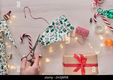 Weihnachtskomposition. Geschenkschachteln, Geschenkverpackungen mit Papier und Band, Lichter, Süßigkeiten Stöcke auf Holz Hintergrund. Holdiay DIY handgemachte Haus dekorat Stockfoto
