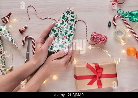 Weihnachtskomposition. Geschenkschachteln, Geschenkverpackungen mit Papier und Band, Lichter, Süßigkeiten Stöcke auf Holz Hintergrund. Holdiay DIY handgemachte Haus dekorat Stockfoto