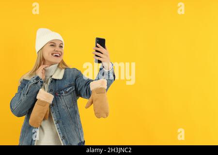 Attraktive Mädchen in Winterkleidung nehmen Sie ein Selfie auf gelben backgroundю Stockfoto