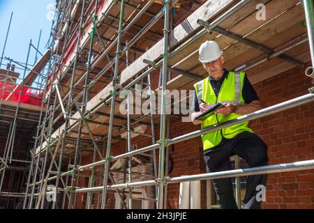 Männlicher Baumeister Vorarbeiter, Bauarbeiter, Auftragnehmer oder Architekt auf Baustelle Schreiben auf schwarzem Klemmbrett Stockfoto