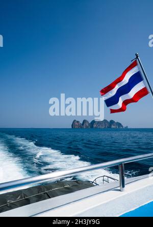 Thailändische Flagge auf dem Boot über dem wunderschönen Meer und dem sommerblauen Himmel im Hintergrund Stockfoto