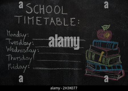 Stundenplan der Schule und Stapel von Büchern mit Apfel auf schwarzer Tafel gezeichnet Stockfoto