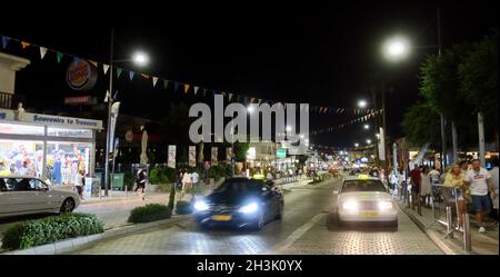 Ayia Napa, Zypern - 14. Oktober 2021: Typische Taxiwagen mit einem ausgedehnten Bodys entlang einer der zentralsten und belebtesten Straßen, gesäumt von schönen Stockfoto