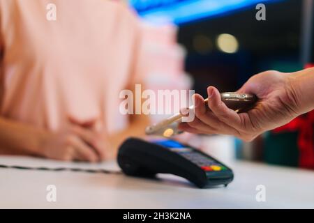 Nahaufnahme von nicht erkennbaren Mann, der mit NFC-Technologie mit Smartphone-Kreditkartenanwendung am POS-Terminal bezahlt, selektiver Fokus. Stockfoto