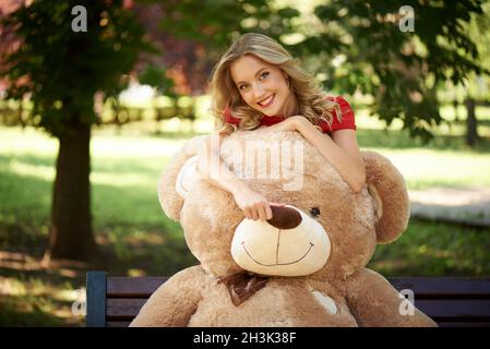 Glückliche junge Frau mit einem riesigen Teddybären. Stockfoto