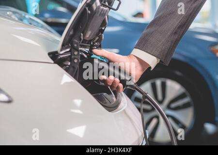 Nahaufnahme des Menschen, der das Elektroauto auflädt. Stockfoto