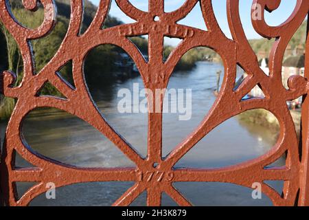 Nahaufnahme der zentralen Dekoration rot von der Ironbridge. Blick durch den Fluss, blauen Himmel und Häuser am Flussufer an einem sonnigen Tag im Winter Stockfoto