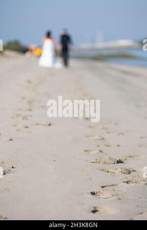 Unbekanntes, frisch verheiratetes Paar, das am Strand spazieren ging Stockfoto