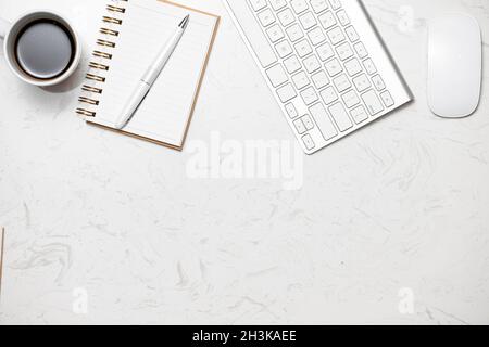 Tasse Kaffee mit Computertastatur und geöffnetem Notebook auf Marmortisch Stockfoto