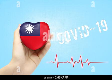 Ein Mädchen hält ein Spielzeug in Form eines Herzens mit der Flagge Taiwans, einem Konzept der Gesundheitsversorgung während der Covid-19-Coronavirus-Pandemie Stockfoto