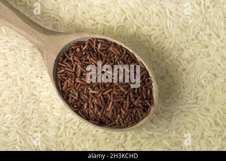 Roter Reis in einem Holzlöffel auf weißem Reishintergrund Stockfoto