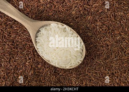 Weißer Reis in einem Holzlöffel auf rotem Reishintergrund Stockfoto