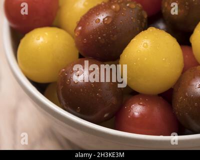 Kirschtomaten in Keramikschale auf Holzhintergrund. Stockfoto