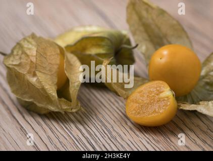 Physalis-Frucht (Physalis peruviana) mit Schale auf Holzgrund. Stockfoto