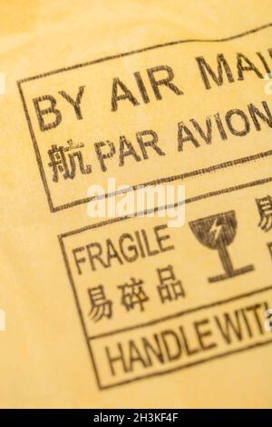 Chinesisches Par Avion-Luftpostetikett auf gelb-braunem Briefumschlagversand/Paket aus China. Für chinesische Exporte, Werkstatt der Welt. Fokus auf „Par“ Stockfoto