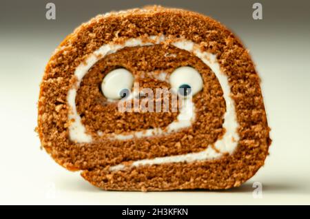 Schokoladen-Biskuitrolle mit Vanillegeschmack, Füllung mit dekorieren süßen Augen, Schokolade schweizer Rolle, lustiges Essen Stockfoto
