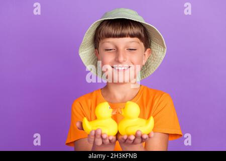 Foto Porträt kleiner Junge trägt Kopfbedeckung halten Gummienten lächeln isoliert pastelllila Farbe Hintergrund Stockfoto