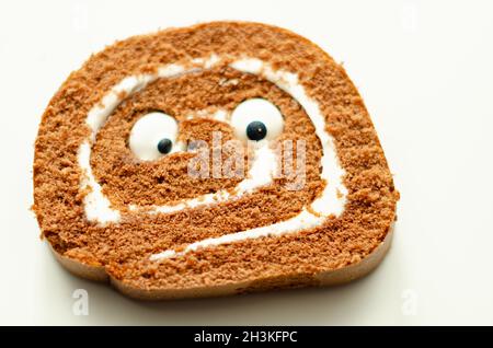 Schokoladen-Biskuitrolle mit Vanillegeschmack, Füllung mit dekorieren süßen Augen, Schokolade schweizer Rolle, lustiges Essen Stockfoto