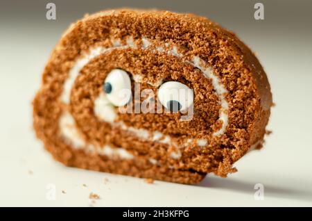Schokoladen-Biskuitrolle mit Vanillegeschmack, Füllung mit dekorieren süßen Augen, Schokolade schweizer Rolle, lustiges Essen Stockfoto