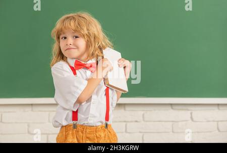 Kindheitsentwicklung. Kind mit Buch. Kopierraum. Fröhlicher Teenager-Junge im Klassenzimmer. Stockfoto