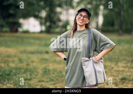 Junge Frau mit Brille mit leerer Öko-Tasche aus Baumwolle, Mockup-Design. Stockfoto