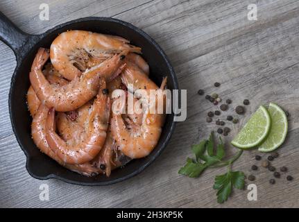 Gegrillte Garnelen Garnelen in einer Pfanne mit Gewürzen, auf Holz- Hintergrund. Ansicht von oben. Stockfoto