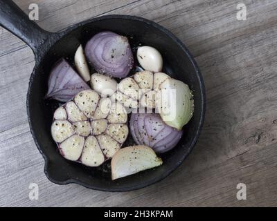 Scheiben Knoblauch, rote und gelbe Zwiebel in einer Pfanne mit Gewürzen, auf Holz- Hintergrund. Ansicht von oben. Stockfoto