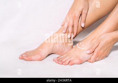 Frau, die Beine Creme, Lotion oder Feuchtigkeitscreme. Hautpflege. Schöne Frau Füße mit Creme Stockfoto