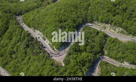 Curvy windigen Straße zwischen Green Mountain Forest, von oben nach unten Luftbild. Sommer Landschaft. Stockfoto