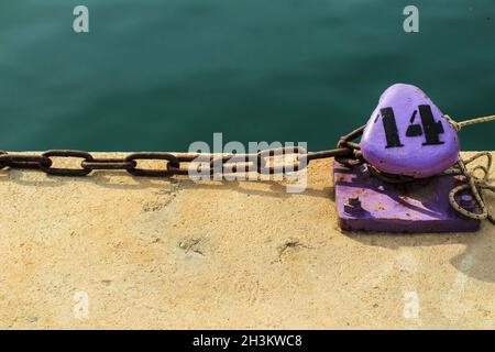 Lila Ankerplatz Poller mit gefesselten rostigen Kette im Hafen von Santa Pola, Alicante, Spanien Stockfoto