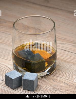 Glas mit Whiskey und Whisky Steine auf Holz- Hintergrund Stockfoto