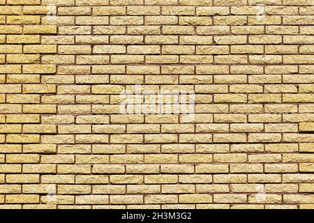 Gelbe dekorative Backsteinwand-Struktur. Abstrakter Hintergrund für Design. Stockfoto