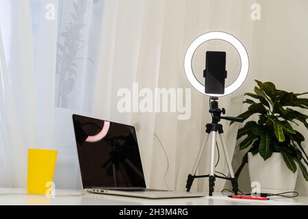 Laptop, Lampe und Stativ auf dem Tisch für Online-Interviews Stockfoto