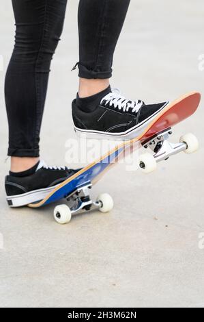 Nahaufnahme der Füße von Teens auf einem Skateboard, das bereit ist, eine Fahrt über die Halfpipe zu beginnen. Stockfoto