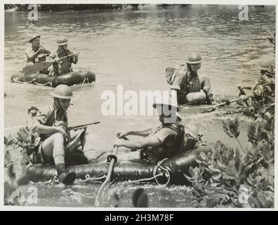 Ein Vintage-Foto aus dem Jahr 1941, das Soldaten der australischen Armee während der japanischen Invasion von Malaya und dem Fall Singapurs in aufblasbaren Gummibooten über einen Dschungelfluss zeigt Stockfoto