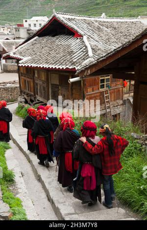 Eine Gruppe buddhistischer Gläubiger geht einen Fußweg/Pfad von einem kleinen Tempel über der Stadt; tibetische Frauen/ethnische Frauen Tibets, wohnhaft oder ortsansässig in die von Mauern umgebene chinesische Stadt Songpan im Norden von Sichuan, China. Im Buddhismus kann eine Frau Nonne sein. (125) Stockfoto