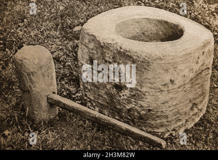 1908 Pressefoto - Ein Klopfstein & Mell aus Orkney, Schottland . Klopfsteine, auch bekannt als Knockin stanes oder Clach chnotainn, waren freistehende oder freiliegende Felsgesteine mit einer in sie geschnittenen, topfförmigen Konkavität, die zum Schälen von Gerste und anderen Körnern verwendet wurde. Sie waren in der Tat eine Art heimische Maismühle in Form eines riesigen Stößels und Mörtels. Stockfoto