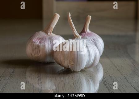 Drei Knoblauchzwiebeln auf einer reflektierenden Oberfläche. Stockfoto