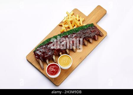 Shashlik oder gegrillte Fleischrippen mit Sauce und Zwiebel mit Pommes auf Holzbrett Weißer Hintergrund Food Sales Concept Ready-to-Use-Menü. Stockfoto