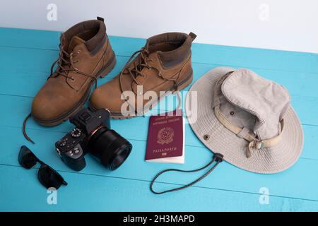 Eine Kamera, ein Hut und ein Paar Schuhe auf einer farbigen Oberfläche Stockfoto