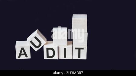 AUDIT-Wort auf Holzblock und schwarzem Hintergrund geschrieben Stockfoto
