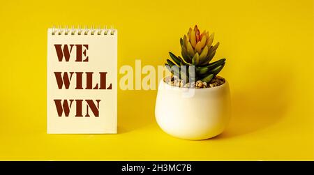 We will Win, Text auf Notizblock, gelber Hintergrund Stockfoto