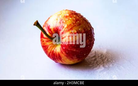 Frischer roter Apfel mit Wasser auf isoliertem blauem Hintergrund Stockfoto