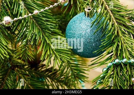 Glänzende blaue Kugel, die auf dem immergrünen Christbaumzweig hängt. Weihnachtsferien Postkarten und Hintergründe Stockfoto