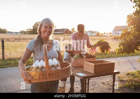 Porträt einer älteren Bäuerin, die Eier im Korb hält Stockfoto