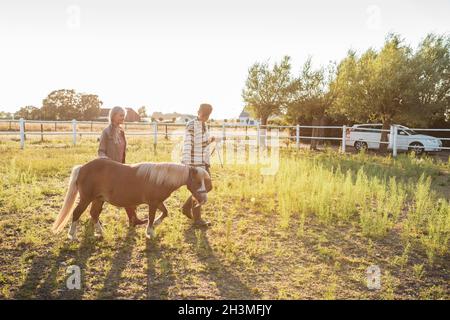 Frau, die mit älterer Mutter und Pferd auf dem Bauernhof läuft Stockfoto