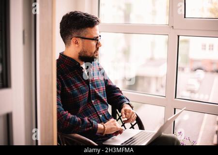 Ernsthaft nachdenklicher Mann mit Laptop-Computer zu Hause Stockfoto